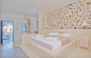 sypialnia z dużym łóżkiem i kamienną ścianą w obiekcie Anatoli Luxury Studios & Suites w mieście Astypalea