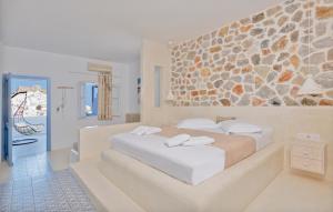 een slaapkamer met een groot bed en een stenen muur bij Anatoli Luxury Studios & Suites in Astypalaia-stad (Chora)