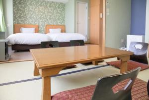 Kur and Hotel Suruga في شيزوكا: غرفة مع طاولة وسرير