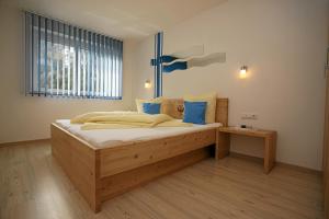 Un dormitorio con una gran cama de madera con almohadas azules en Apart Knabl, en Sankt Leonhard im Pitztal