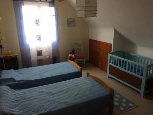 a bedroom with two beds and a crib and a window at aux 2 oies in Plouider