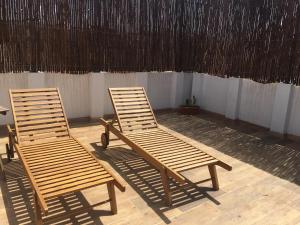 two wooden chairs sitting in front of a wall at Casa Campillo, Habitaciones Individuales in Telde