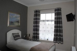 a bedroom with a bed and a window with curtains at Abbey Grange Hotel in Nuneaton