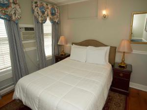 a bedroom with a white bed and two windows at Bellevue House in Newport