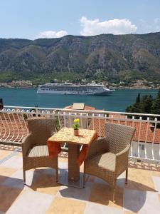 a table and chairs on a balcony with a cruise ship at Apartments Peranovic 2 in Kotor