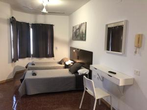 a bedroom with a bed and a table and a desk at Hostal Tamonante in Gran Tarajal