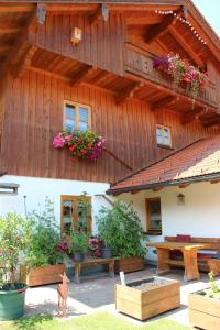 una casa in legno con un tavolo e fiori di Ferienwohnung Uschi Willibald a Wackersberg