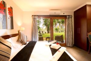 a hotel room with a bed and a sliding glass door at Rio Vista Lodge in Malelane