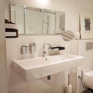 uma casa de banho branca com um lavatório e um espelho em Chambre d hotes "Lilimyna" avec petit déjeuner em Barjols