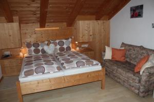 een slaapkamer met een bed en een bank bij Ferienwohnung Uschi Willibald in Wackersberg