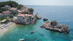 a boat in the water next to a beach at Kazanegra Exclusive Apartments in Sveti Stefan