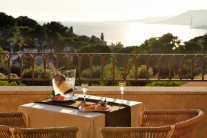 a table with two glasses of wine on a balcony at Hotel Bartaccia in Propriano