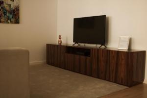 una TV a schermo piatto seduta sopra un centro di intrattenimento in legno di Nightingale Apartments a Porto