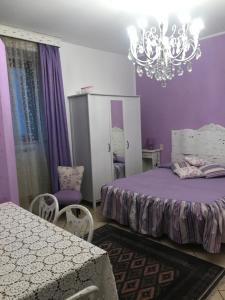 una camera viola con letto e lampadario pendente di Stella Polare B&B a Rieti