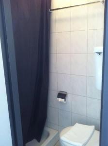 a bathroom with a toilet and a black shower curtain at Hotel Central in Sursee