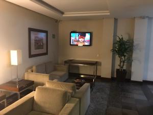 uma sala de estar com sofás e uma televisão na parede em Wall Street Flat Service em Caxias do Sul