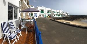 un balcón con sillas y una sombrilla en la playa en Casa El Charco en Orzola