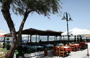 a restaurant with tables and umbrellas on the beach at Rozy House Nei Epivates Thessaloniki ( Near the sea) in Neoi Epivates