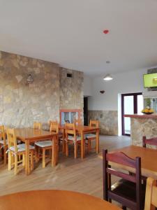 a restaurant with wooden tables and chairs and a stone wall at Sol Mar in Odeceixe