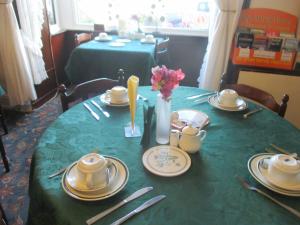 una mesa con un mantel verde con platos y utensilios en Beachcomber en Swansea