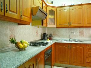 a kitchen with wooden cabinets and a bowl of fruit on the counter at Playa de la Calzada in Sanlúcar de Barrameda