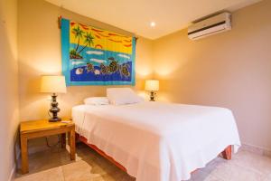 Un dormitorio con una cama blanca y una pintura en la pared en Tamarindo Village Hotel, en Tamarindo