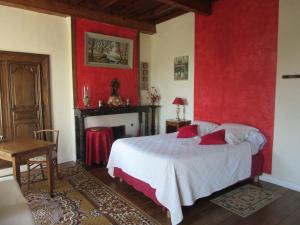 a bedroom with a bed and a red wall at Le haut Manoir in Tourville-sur-Sienne
