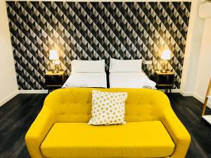 a yellow couch in a room with two beds at Apartamentos Arriba by gaiarooms in Salamanca