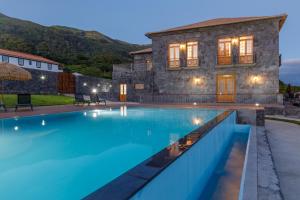 a villa with a swimming pool in front of a building at Quinta da Magnólia AR in Urzelina