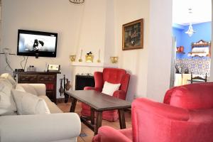 a living room with red chairs and a table and a tv at Casa Azul in Alozaina