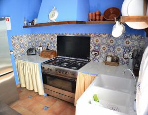 cocina pequeña con fogones y paredes azules en Casa Azul en Alozaina
