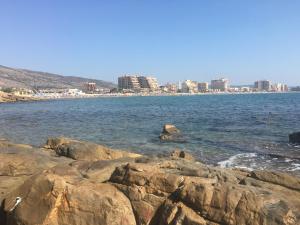 a beach with rocks and a city in the background at Apartamentos Entreplayas in Oropesa del Mar