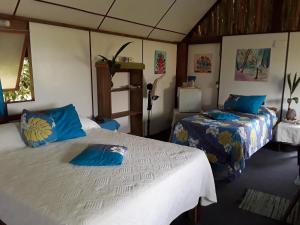 1 dormitorio con 2 camas y almohadas azules en Tifaifai Et Café Huahine, en Fare