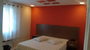 a bedroom with a bed with an orange wall at Golfinho Hotel (Adults Only) in São Vicente