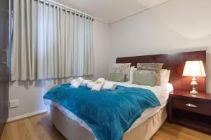 a bedroom with a large bed with a blue blanket at Lagoon Beach 136 by CTHA in Cape Town
