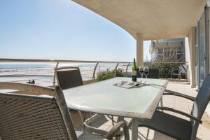 a table and chairs on a balcony with a view of the beach at Lagoon Beach 136 by CTHA in Cape Town