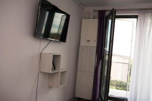 a room with a tv on a wall with shelves at Apartament Serenity Mamaia Nord in Mamaia Sat/Năvodari