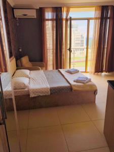 een slaapkamer met een bed en een groot raam bij Orbi Plaza Apartment in Batoemi