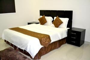 ein Schlafzimmer mit einem großen Bett mit weißer Bettwäsche und Kissen in der Unterkunft الخربوش للشقق المخدومة in Hafar Al-Batin