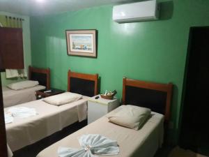 two beds in a room with green walls at Pousada Rural Veredas in Três Marias