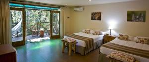 a hotel room with two beds and a balcony at Tierra Guaraní Lodge in Puerto Iguazú