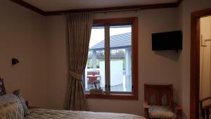 a bedroom with a bed and a window with a television at Bruntwoodlodge in Cambridge