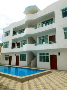 a building with a swimming pool in front of it at Hotel Villa Turquesa in Tonsupa