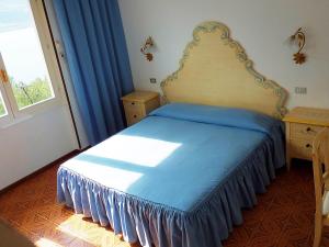 - une chambre avec un lit doté de draps bleus et une fenêtre dans l'établissement Hotel Villa Margherita, à Limone sul Garda