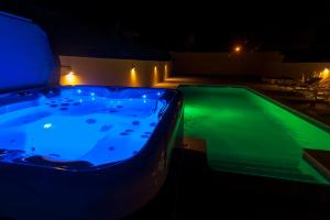 villa Aqua-Jacuzzi-heatable pool-sauna-gym-snooker في ألبوفيرا: حوض استحمام ساخن مع إضاءة زرقاء بجوار حمام سباحة