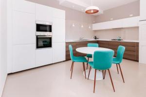 a kitchen with white cabinets and a table and chairs at Alchimia Apartment in Conversano