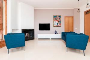 ein Wohnzimmer mit 2 blauen Stühlen und einem TV in der Unterkunft Alchimia Apartment in Conversano