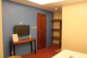 Habitación con escritorio y TV en la pared. en Aqua Travel Lodge en El Nido