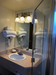 een badkamer met een wastafel, een spiegel en handdoeken bij A1 Choice Inn in Mount Shasta