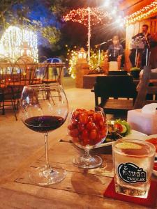 a table with a glass of wine and a plate of fruit at Saimoonbury Resort in Ban Huai Phai Yai